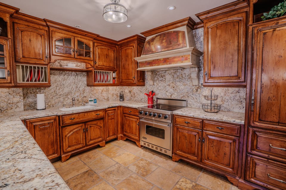 A large, modern fully equipped kitchen featuring stainless steel appliances, sleek European-style finishes, and convenient bar seating for casual dining.