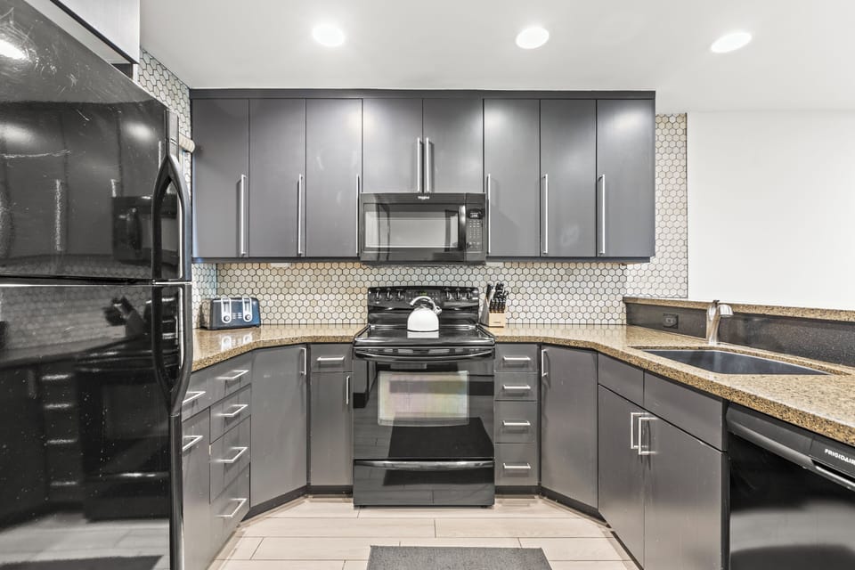 Snow Flower 126 offers a well equipped kitchen with grey cabinets, granite countertops, and tiled backsplash.