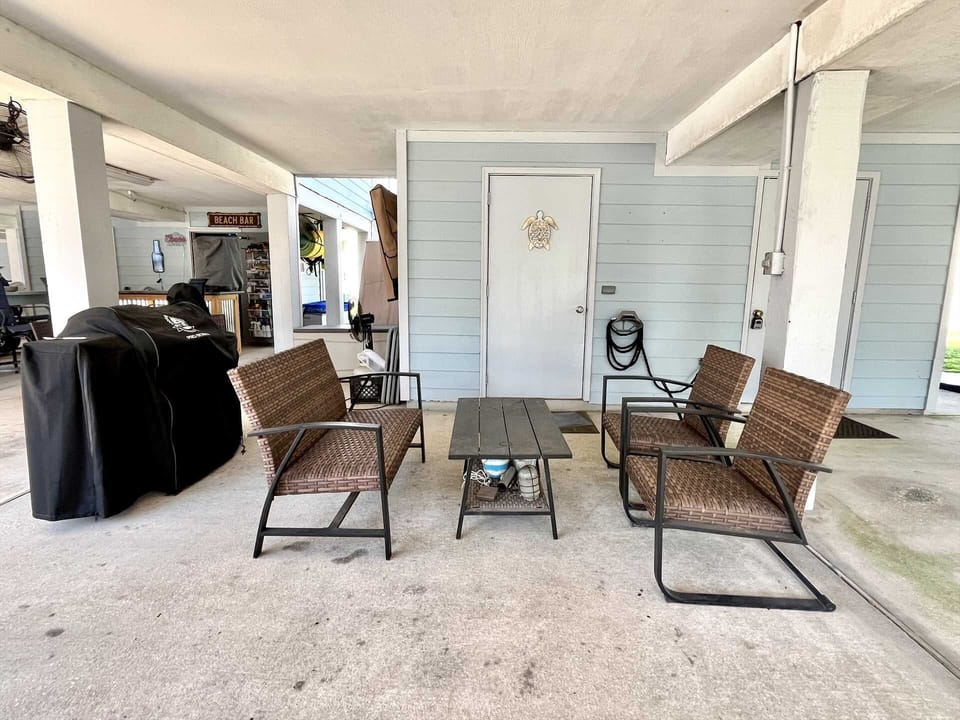 Outdoor table & chairs beside the charcoal grill (carport).
