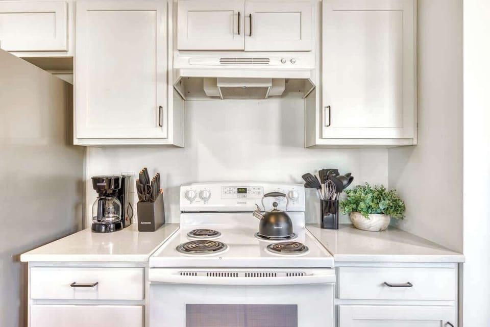 Kitchen with range and white cabinetry.