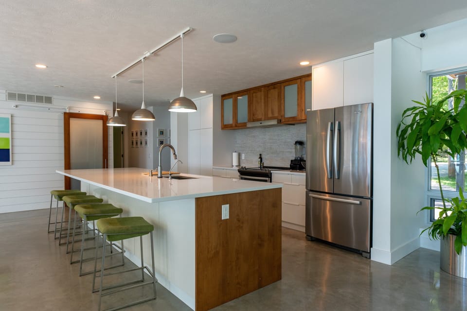 🍴 Bright, sleek, and guest-ready. Pull up a green stool, pour a drink, and settle into this clean-lined kitchen made for connection and comfort.