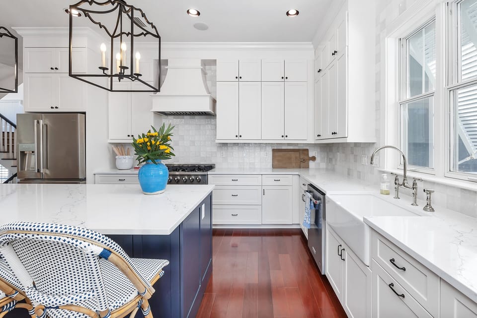 White kitchen with navy island, lantern pendant, stainless appliances