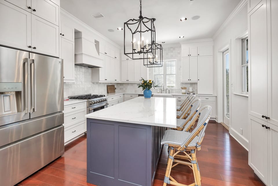 White kitchen with navy island, bar stools, stainless appliances