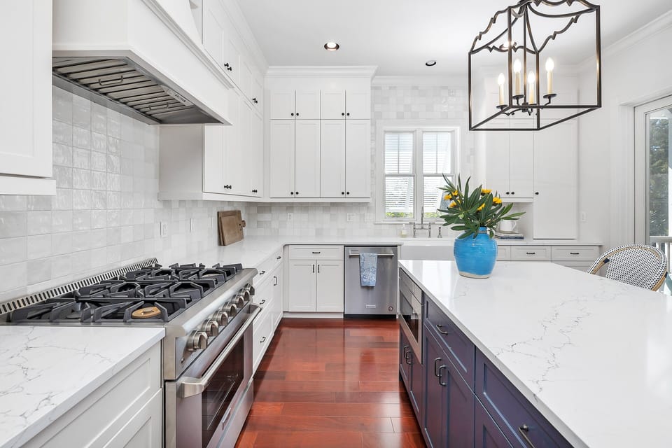 White kitchen with gas range, quartz counters, and pendant light
