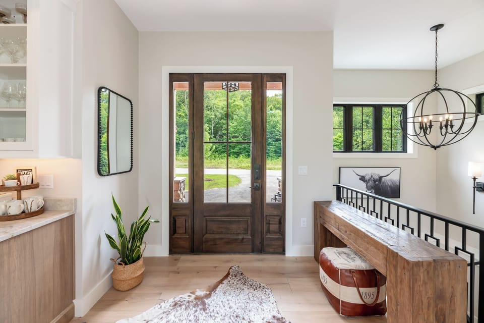 Welcoming entryway with rustic wooden double doors, bright natural light, and stylish décor. A warm introduction to the home’s modern mountain charm.