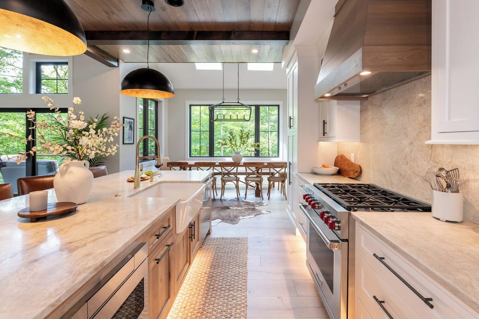 Bright gourmet kitchen with a large island, high-end appliances, and farmhouse sink. Opens to the dining area with big windows and natural light, creating the perfect space for cooking and gathering.