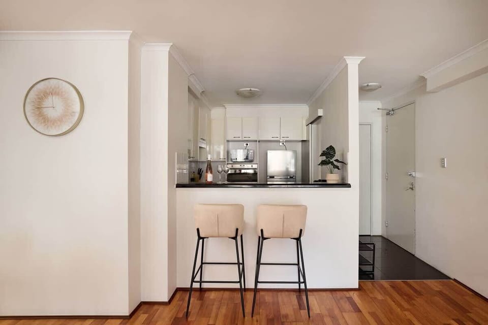 Modern kitchen with breakfast bar seating and premium appliances. Open-plan design with quality finishes creates ideal space for quick meals or casual dining in your city apartment.
