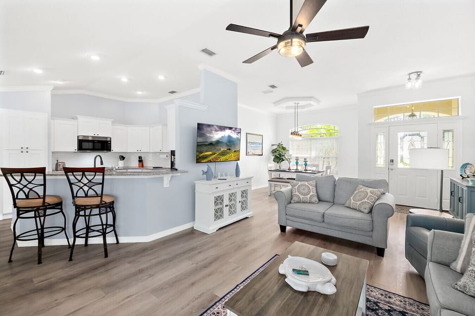 Open-concept living area with stylish coastal décor, breakfast bar seating, and a welcoming flow from the kitchen to the dining and lounge spaces.