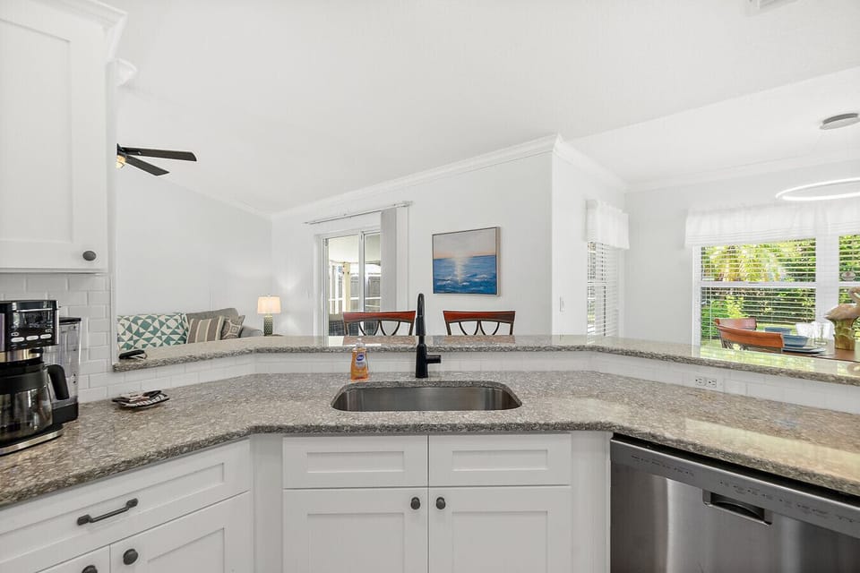 Modern kitchen with granite counters, coffee maker, and breakfast bar seating overlooking the living and dining areas for easy entertaining.