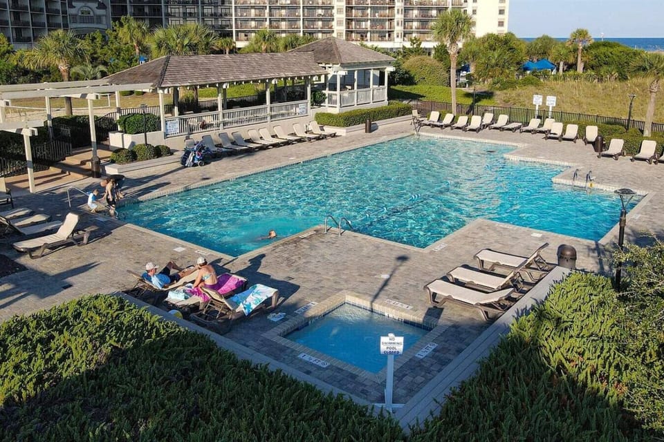 Oceanfront Myrtle Beach pool with hot tub, sun loungers, and poolside beach bar. Just steps from the sandy shore, this resort-style pool area also features convenient outdoor showers; perfect for rinsing off after your Myrtle Beach vacation day.