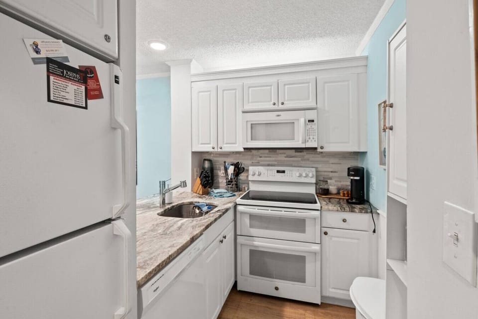 Fully equipped Myrtle Beach vacation rental kitchen with modern appliances: oven with stovetop, microwave, refrigerator/freezer, dishwasher, toaster, Keurig (drip & K-pod), blender, cookware, dinnerware, and silverware; perfect for family meals
