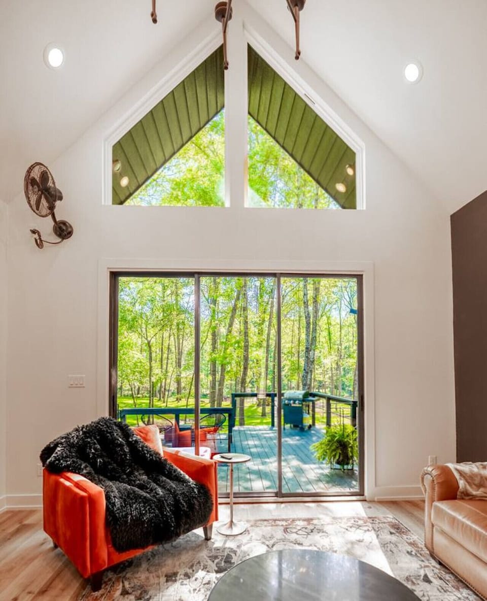 Open living area with expansive windows overlooking the private deck and surrounding woods.