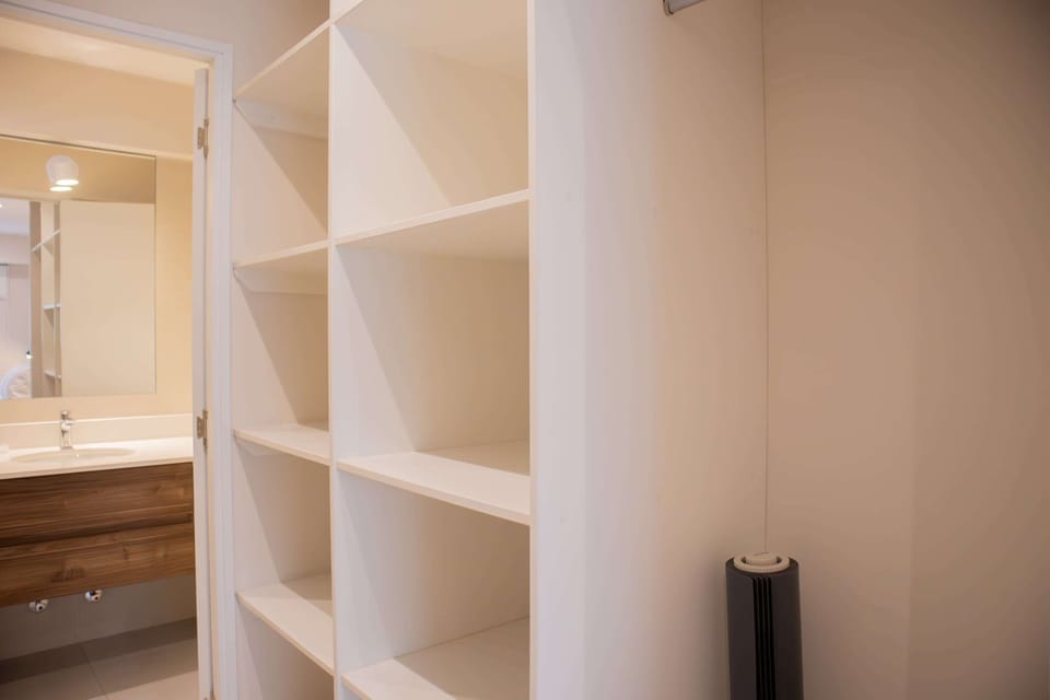 Open closet with shelving and view into the bathroom.