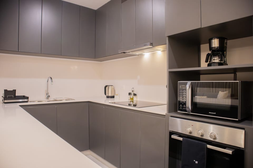 Modern kitchen with sleek gray cabinets, built-in oven, microwave, and small appliances.