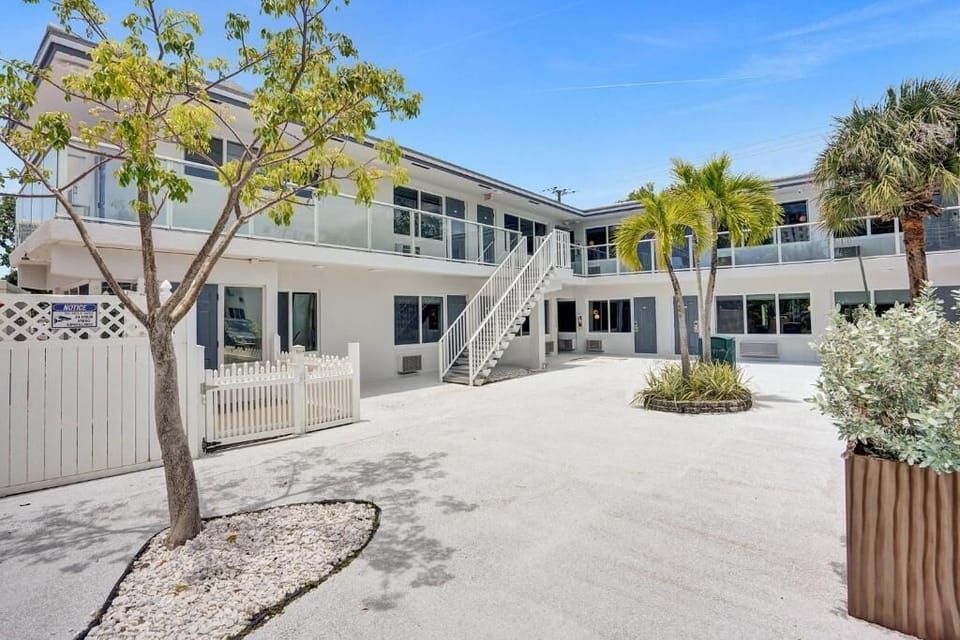 Step into a sunlit courtyard framed by palms and balconies.