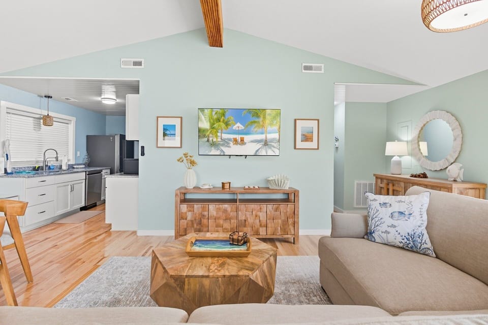 Living Area: Bright, open-concept living area with cathedral ceilings, shiplap accents, and cozy coastal vibes.