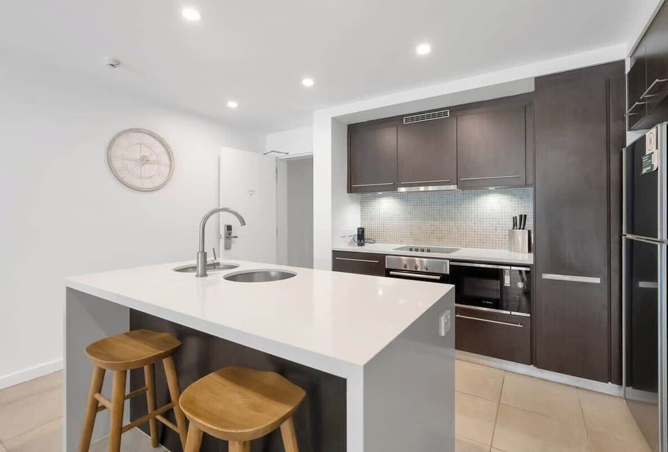 The kitchen blends dark cabinetry and smooth stone finishes with modern appliances, offering everything you need for relaxed, home-style cooking.