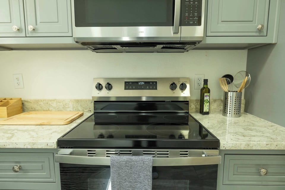 A modern kitchen setup with a sleek stove, microwave, and granite countertops makes cooking easy and enjoyable during your stay