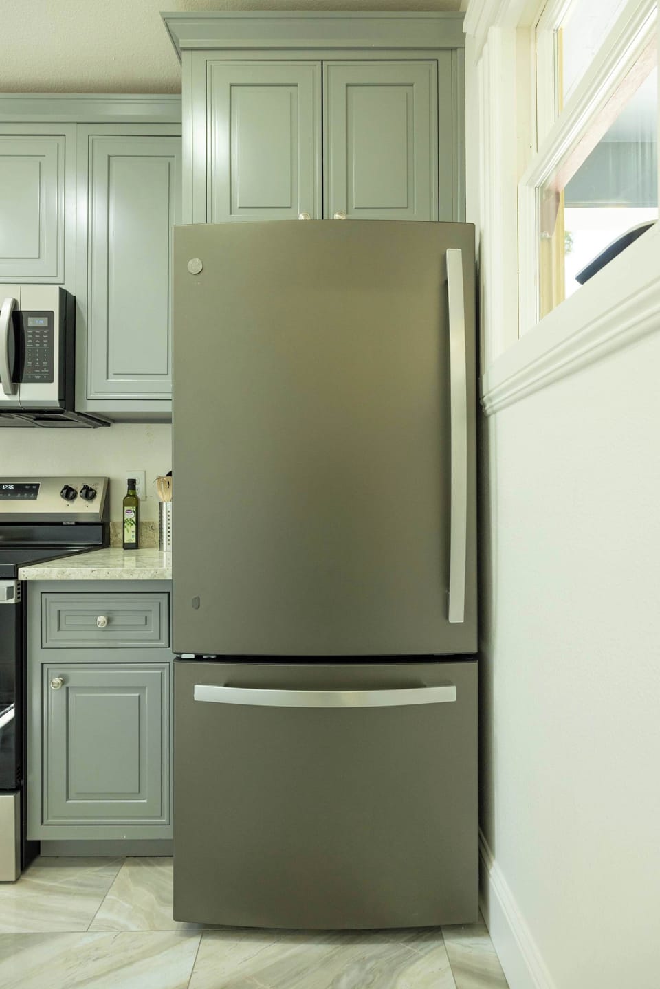 A sleek stainless steel refrigerator complements the soft cabinetry, offering modern convenience and ample storage for all your fresh ingredients and favorite treats