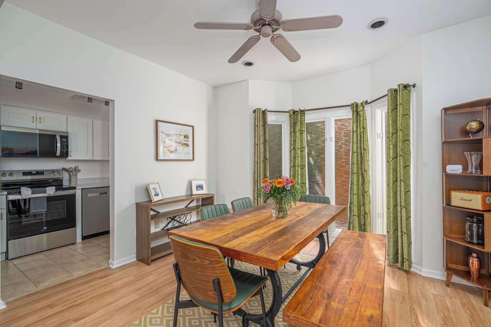 Dine in a naturally lit space with a wooden table positioned near large windows and elegant green curtains!