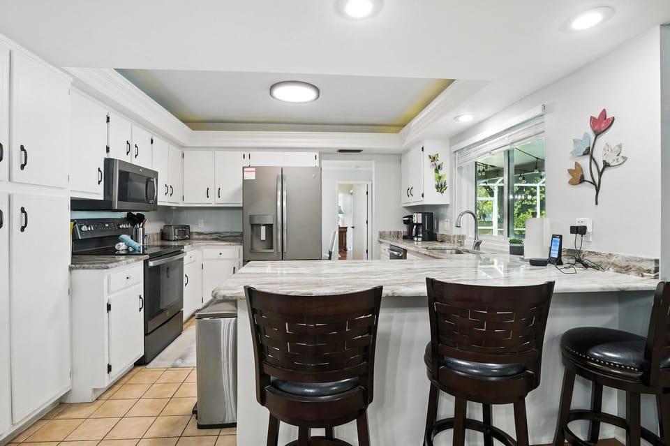 3 seats at kitchen island next to breakfast nook table and family room