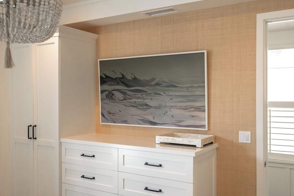 The primary suite features plush bedding, a Frame TV, and timeless design