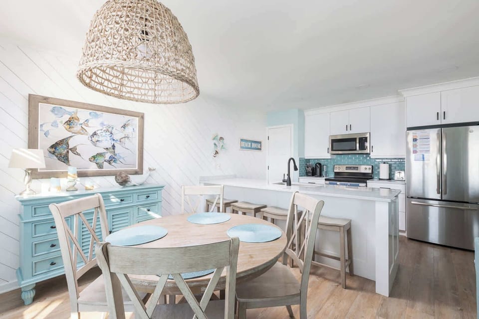 Bright dining and kitchen space on the upper level with easy deck access and open flow (main dining seats 4, bar seating for 4, fully equipped kitchen, and modern appliances)