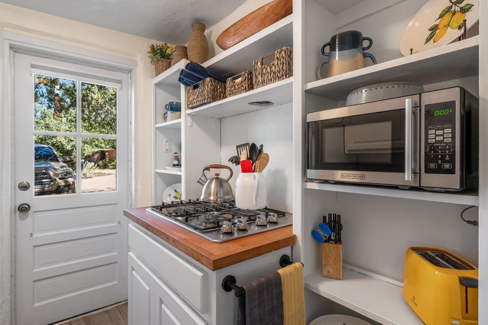 Kitchenette with microwave, stovetop, and full fridge/freezer.