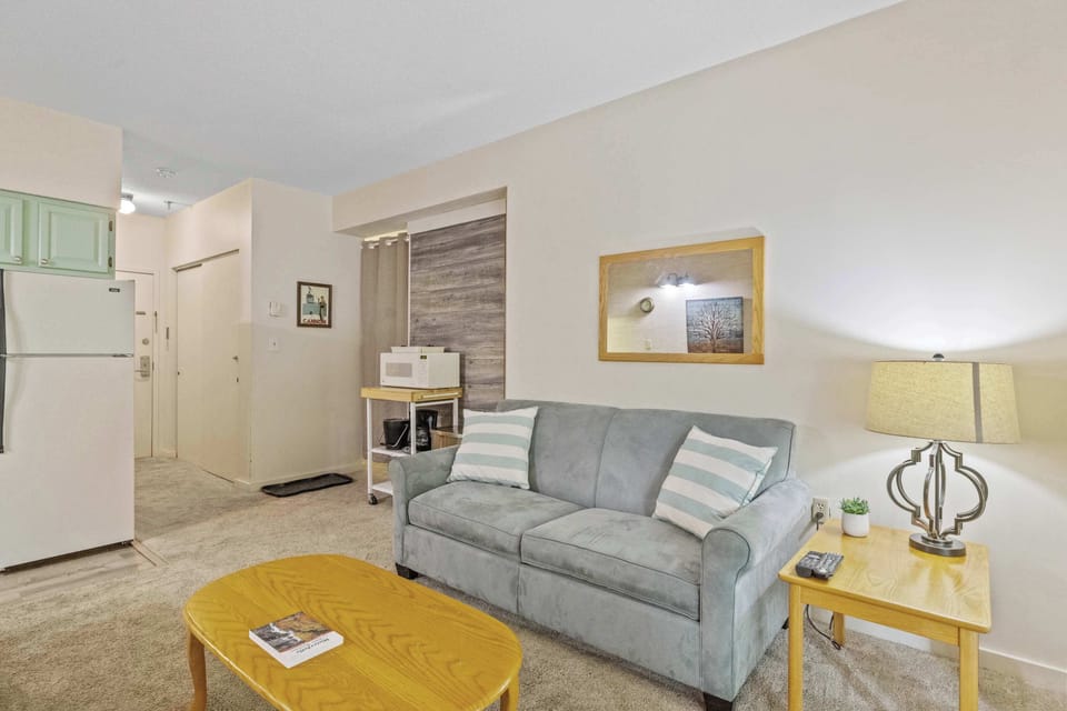 Relax in the open-concept living room, featuring a plush sofa that converts into a full-size sleeper. The layout flows seamlessly into the kitchen, making it easy to cook, dine, and gather together