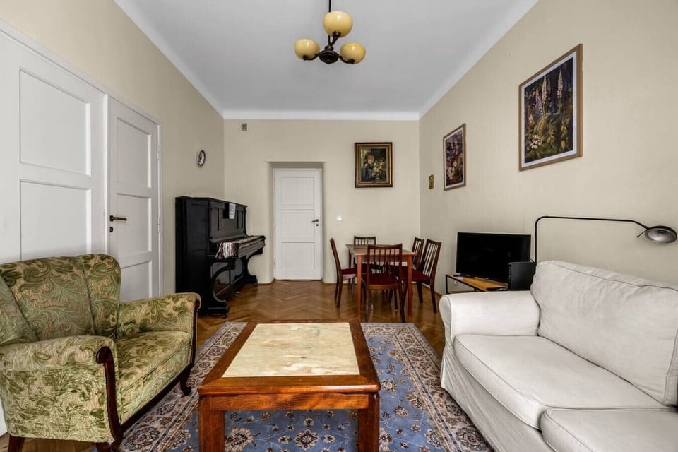 Living Room – Spacious area with sofa, TV, dining table, and even a piano for a touch of charm | Book Now with RENTUJEMY.COM