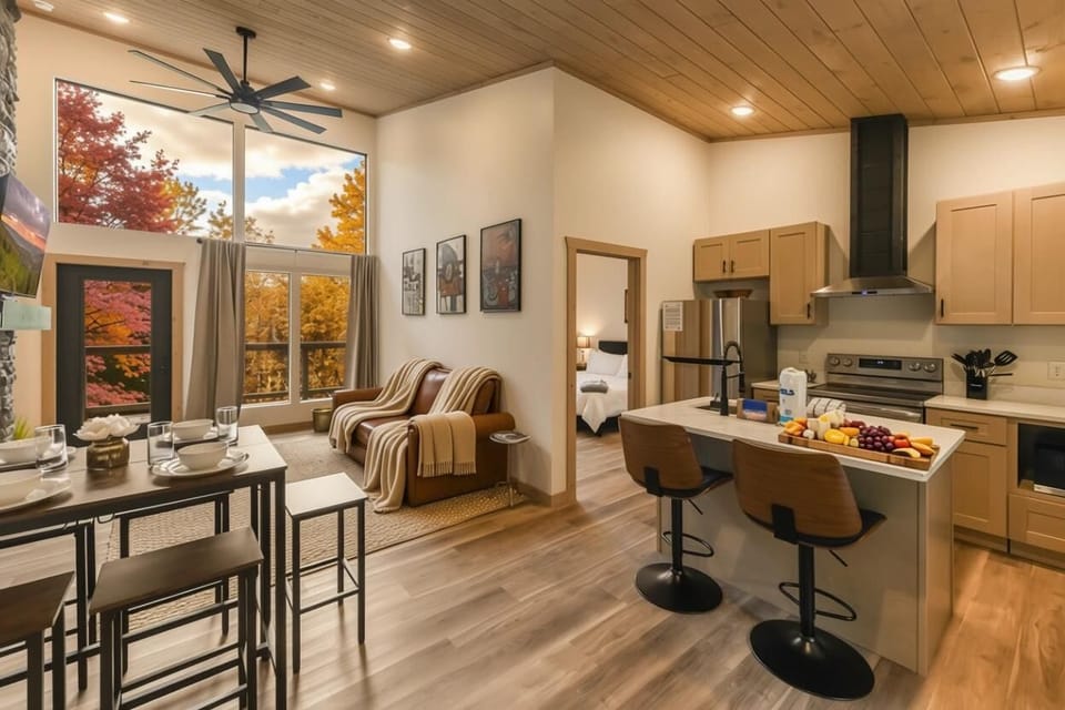 Modern kitchen and living area with large windows showcasing autumn views.