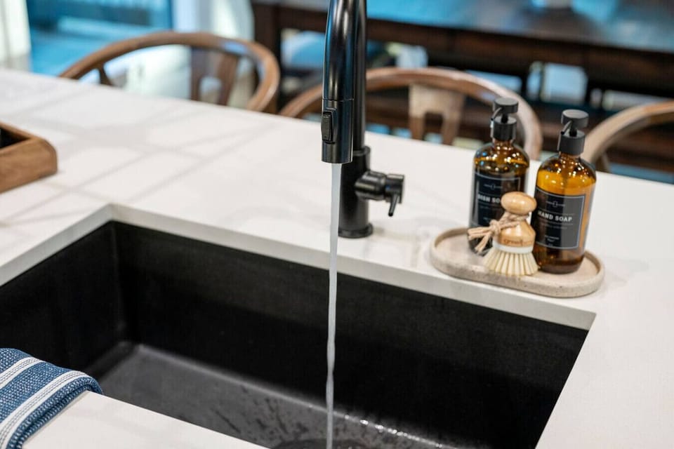 This sleek black faucet with those amber glass bottles and a natural brush sitting on the counter basically tells you that someone thought through every detail of making this kitchen feel both functional and beautiful.