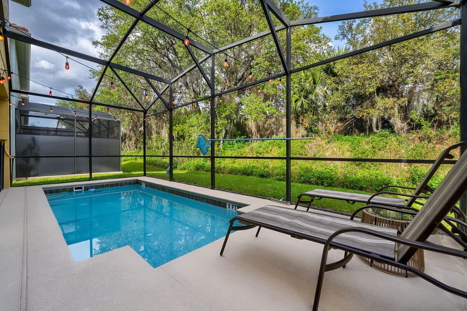 Private screened-in pool with sun loungers and a serene backyard view.