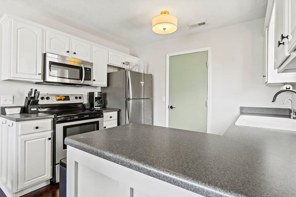 A peek inside the cabinet reveals a full set of cookware, mixing bowls, a toaster, popcorn maker, and crockpot—all ready for your culinary adventures.