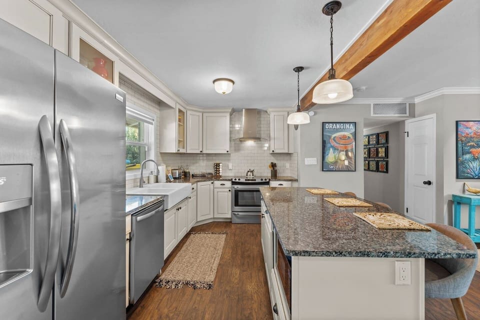 Fully equipped kitchen with stainless appliances, granite island, and subway tile backsplash.