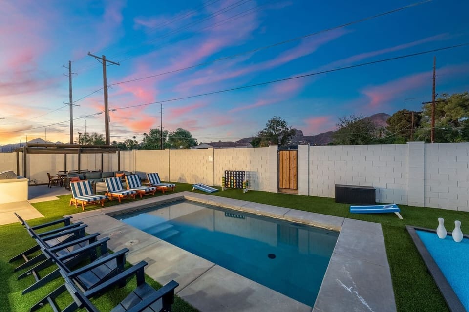 Nightfall gathering zone: pergola seating, dining, and cornhole around the pool.