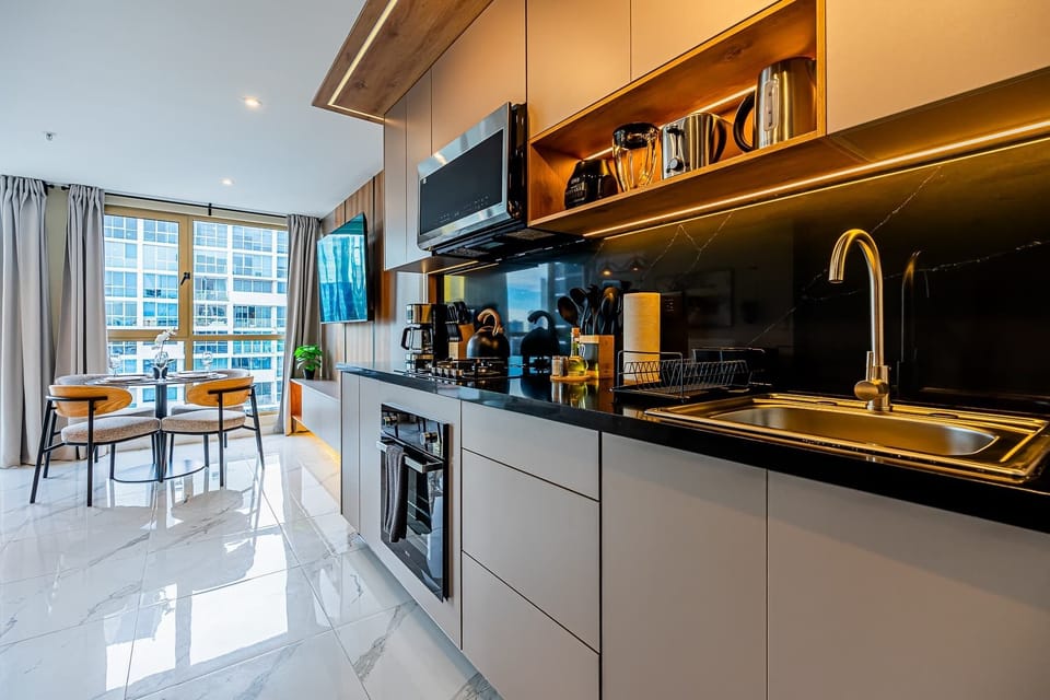 Modern kitchen with dark countertops, open shelving, and warm lighting.