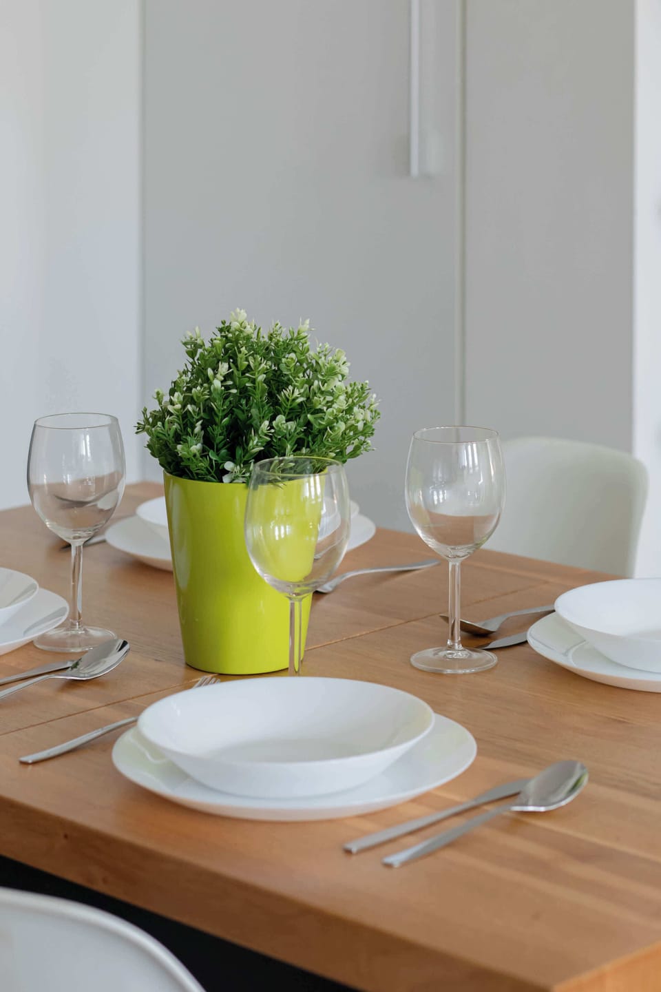 A beautifully set dining table, decorated with elegant wine glasses and a green plant, creating a refined and welcoming atmosphere.