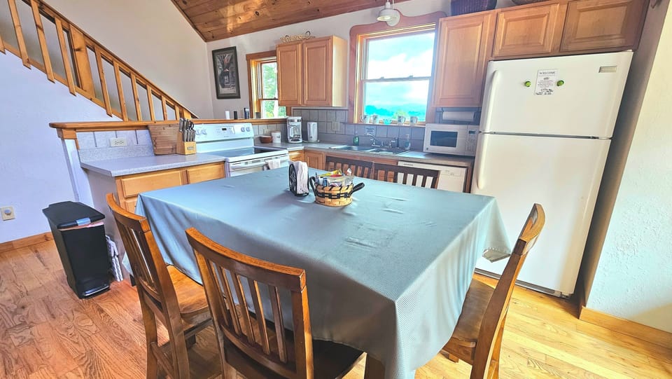 microwave, kitchen visible, coffee and or coffee maker, kitchen, oven, refrigerator, stovetop, dining table