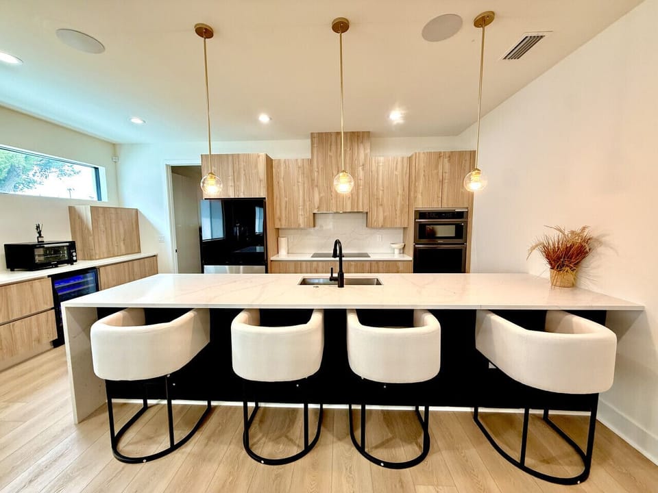 Modern kitchen with sleek wood cabinetry, spacious island seating, and pendant lighting—perfect for cooking and gathering