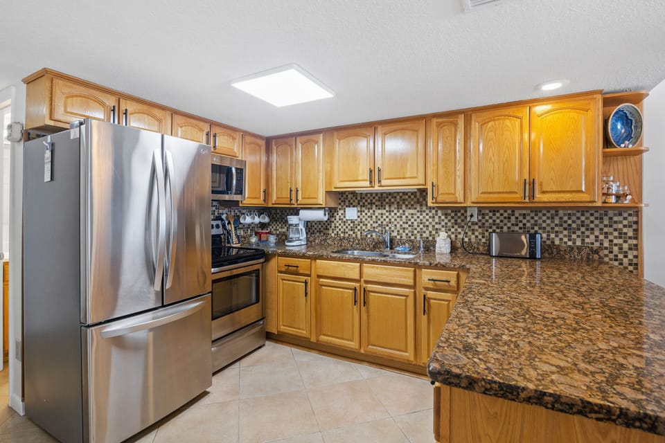 This fully equipped beachside kitchen features stainless steel appliances, granite countertops, and warm cabinetry—perfect for preparing seaside meals in style and comfort.
