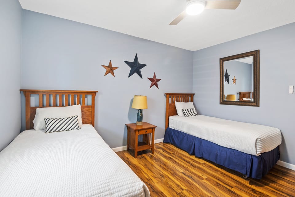 This bright coastal-inspired twin room offers comfort and charm with nautical accents, warm wood furnishings, and beachy décor—perfect for guests enjoying a seaside vacation stay.