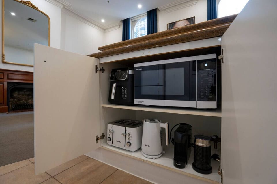 Built in appliance station with microwave, air fryer, toaster, kettle, and coffee makers neatly stored for easy access and everyday convenience.