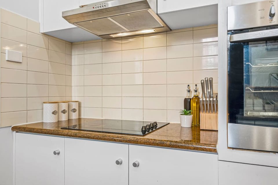 Clean modern kitchen setup with electric cooktop, built in oven, knife set, and cooking essentials ready for easy home style meals during your stay.
