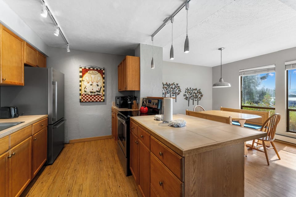 Your spacious kitchen features warm wood cabinetry, modern appliances, and a breakfast bar where you can enjoy morning coffee with scenic views.