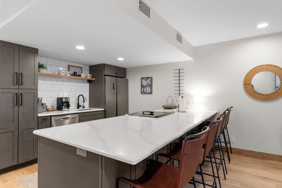 The modern kitchen features stainless steel appliances, and breakfast bar seating.
