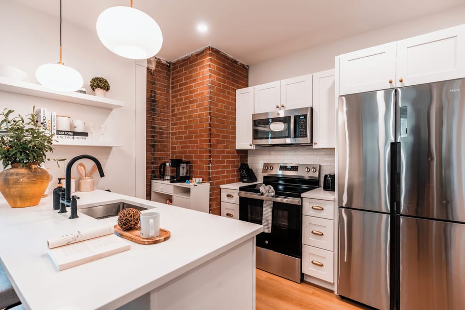 Stylish kitchen with brick accent, modern appliances, and a cozy breakfast bar.