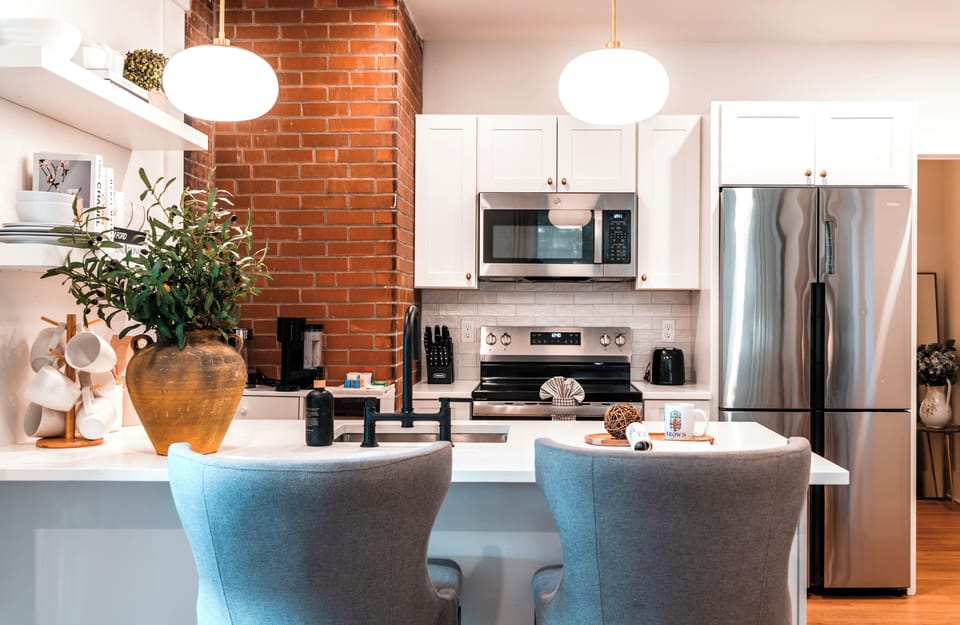 Stylish kitchen with brick accent, modern appliances, and a cozy breakfast bar.