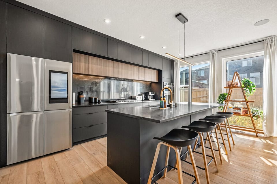 Contemporary kitchen featuring dark cabinetry, stainless steel appliances, and island counter.