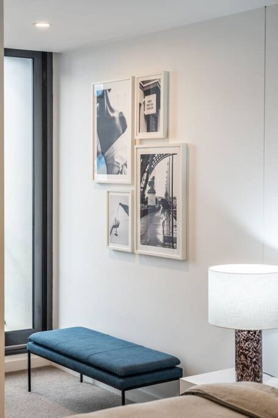 Clean lines and monochrome photography anchor this corner, softened by a deep teal bench.